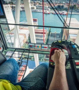 Foreman operating crane at shipping terminal.